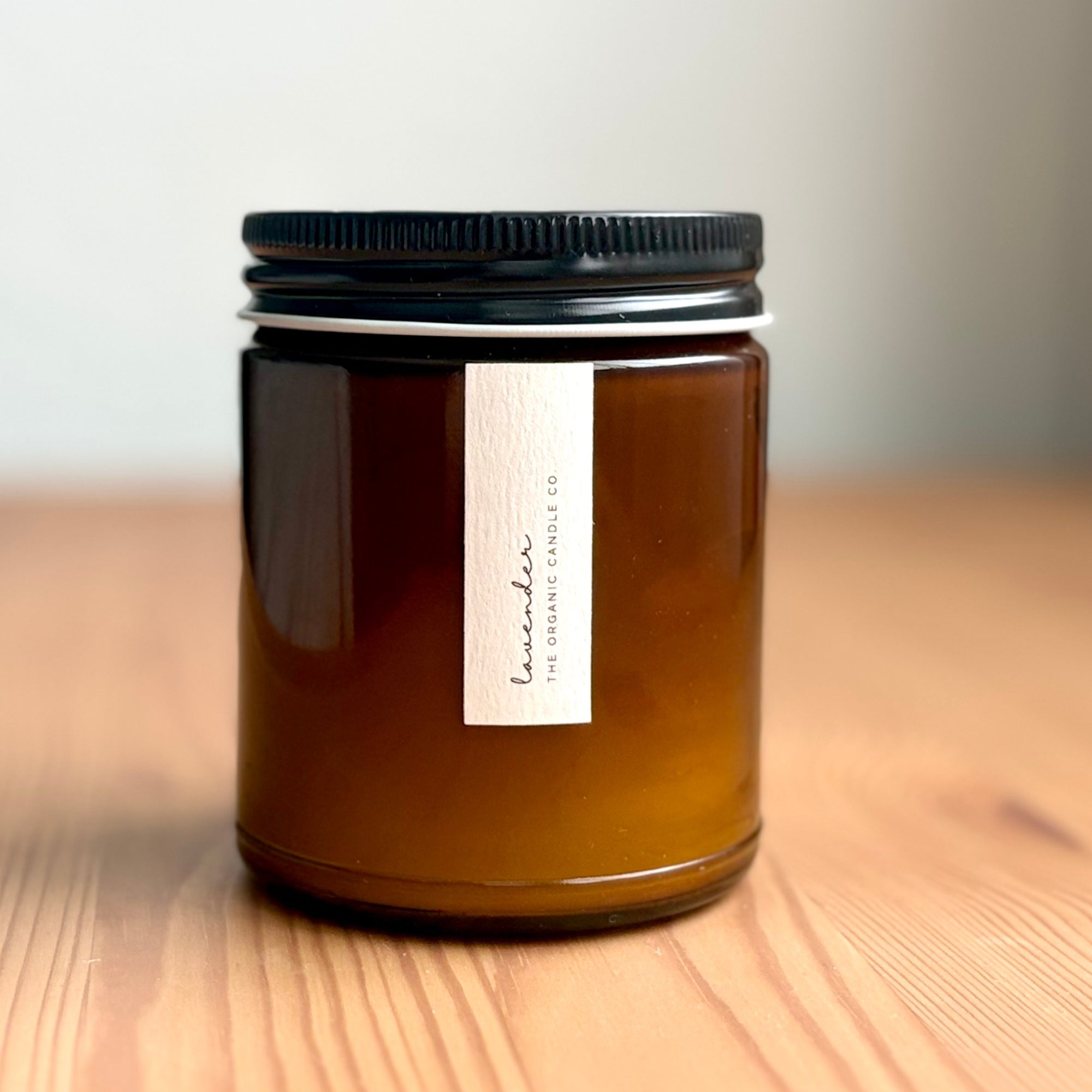 Amber jar organic candle with black lid on a wooden surface