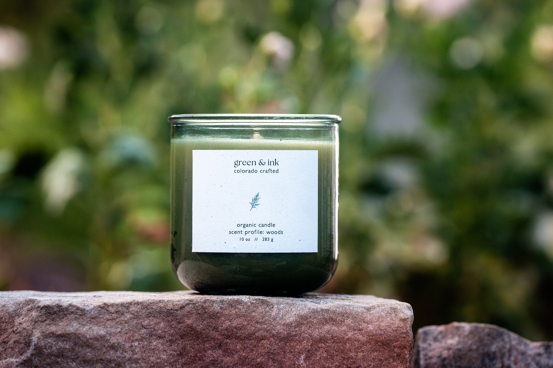 Organic candle in recycled green glass with a label on a stone surface with a blurred green background