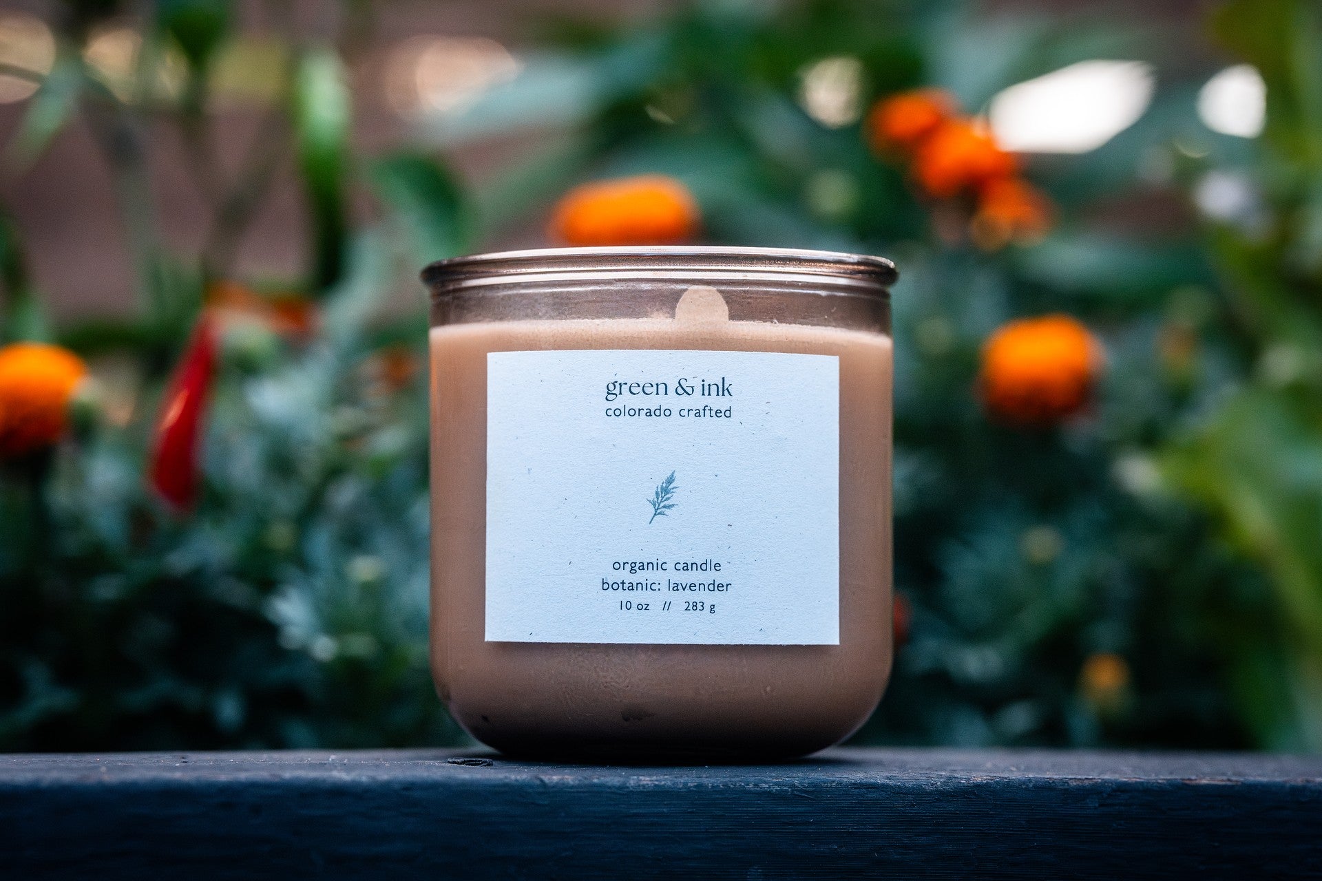 Organic candle in recycled blush-colored glass with a label on a surface with a blurred natural background