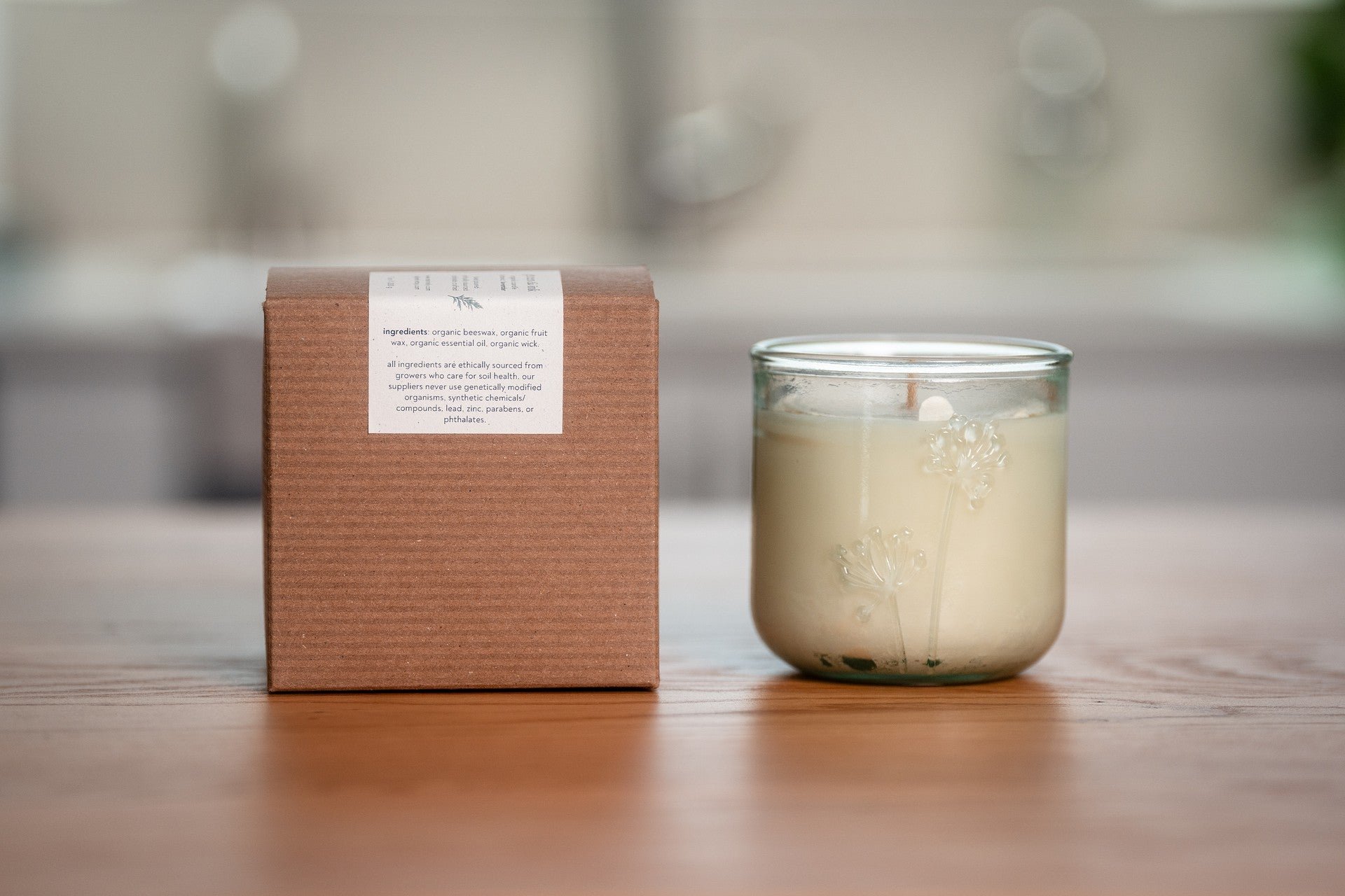 Organic candle in a recycled glass jar with a cardboard box on a wooden surface
