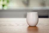 White ceramic organic candle on a wooden surface with a blurred background