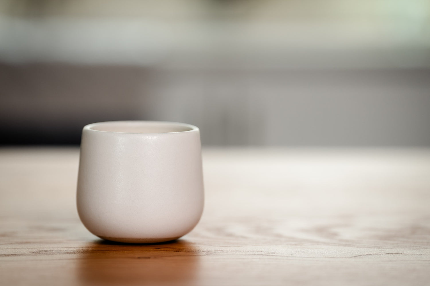 White ceramic organic candle on a wooden surface with a blurred background
