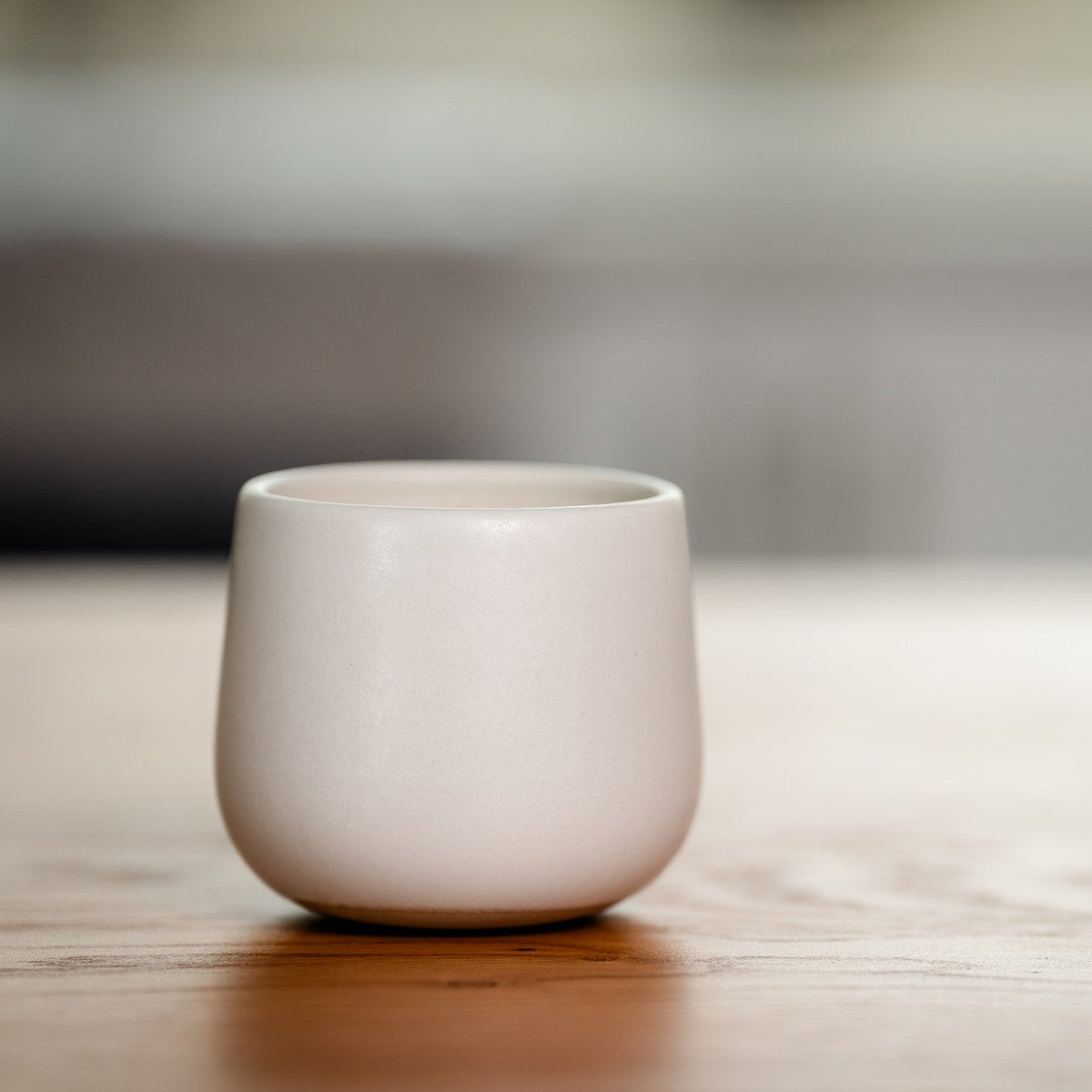White ceramic organic candle on a wooden surface with a blurred background