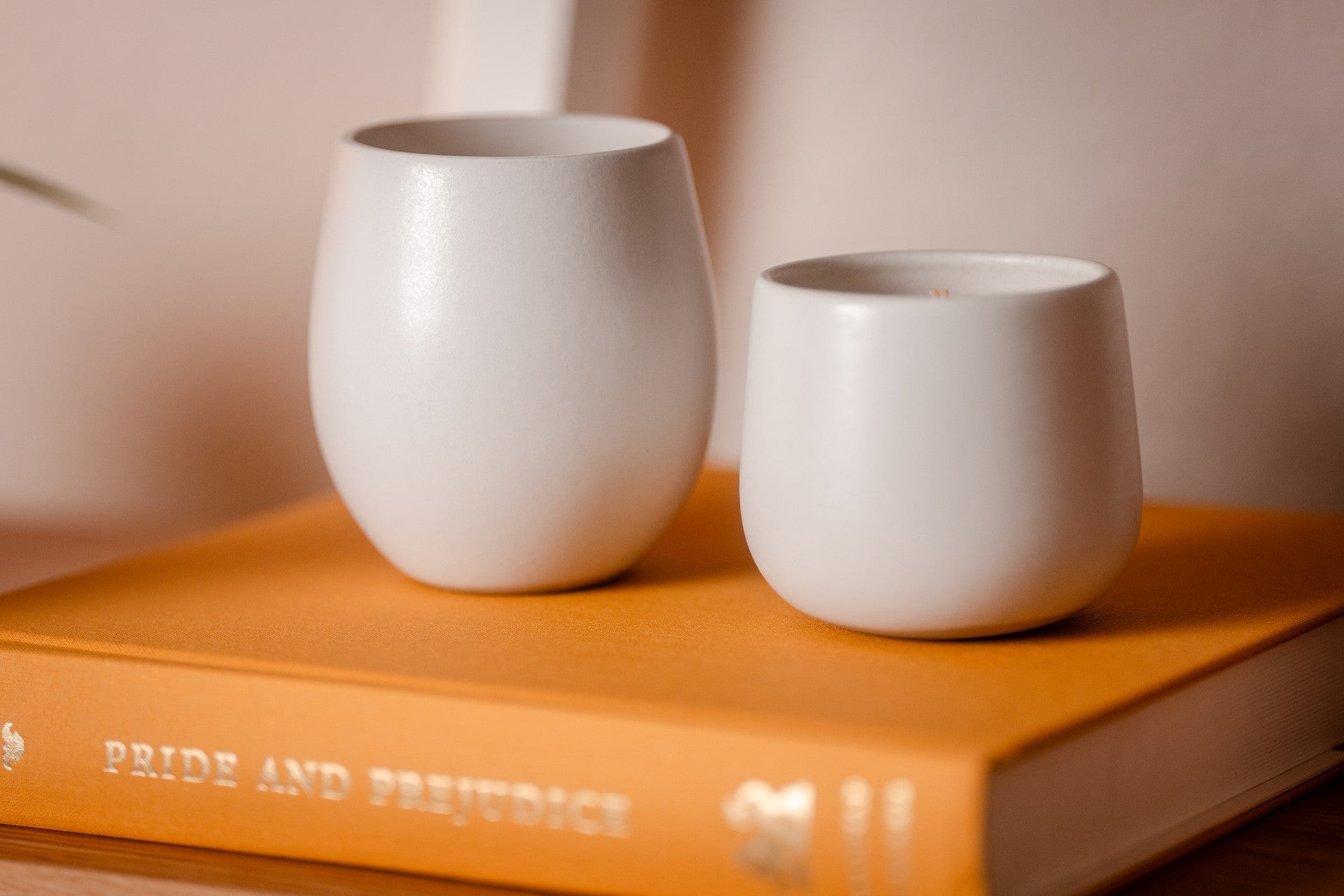 Two white ceramic organic candles on an orange book with a blurred background