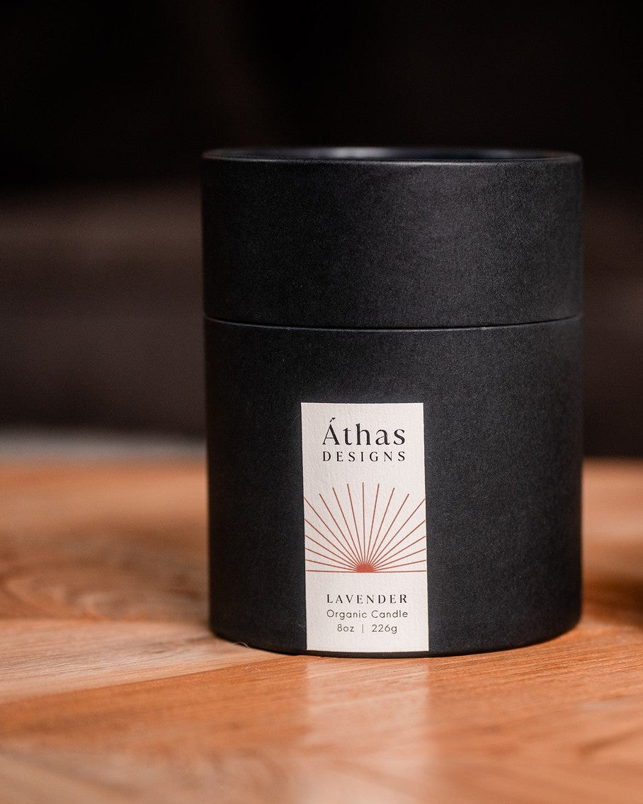 Modern black organic candle container with a label on a wooden surface.