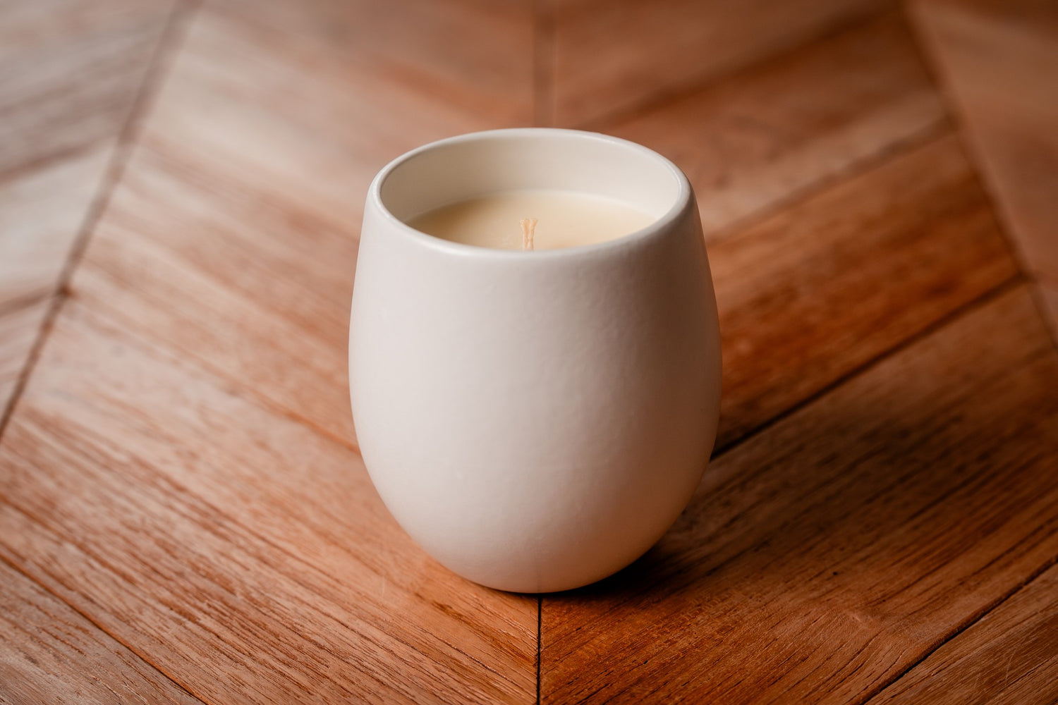 White ceramic organic candle on a wooden surface