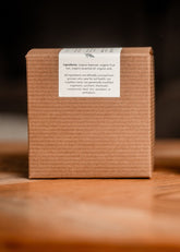 Organic candle and its packaging on a wooden surface with a dark background
