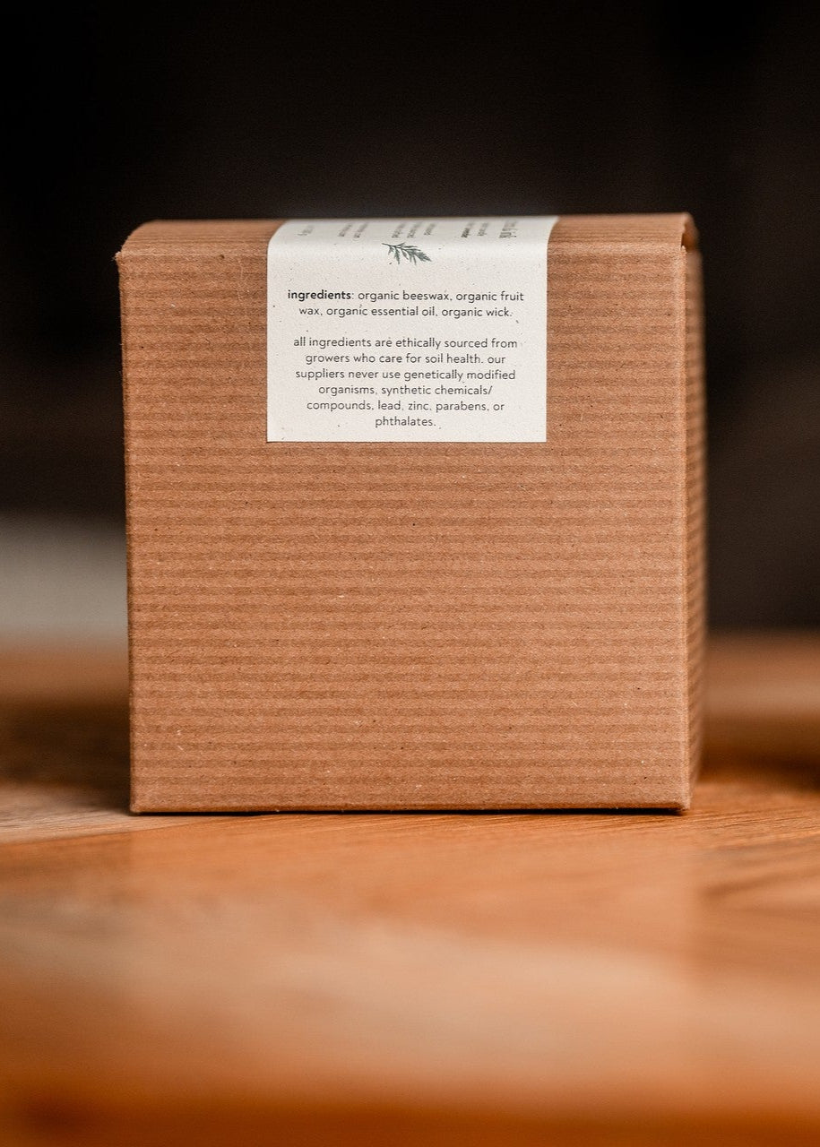 Organic candle and its packaging on a wooden surface with a dark background