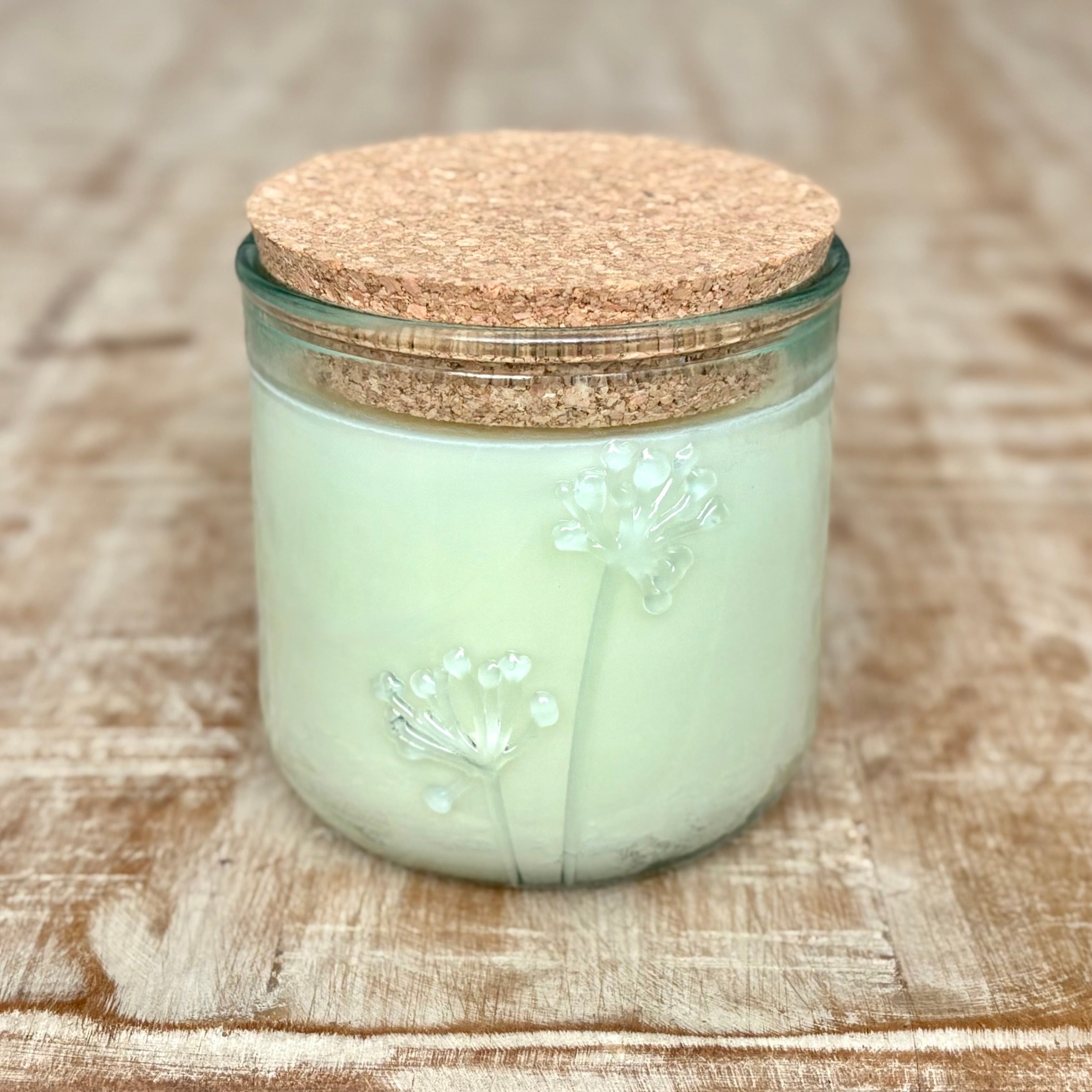 Organic candle in a recycled glass jar with a cork lid on a wooden surface