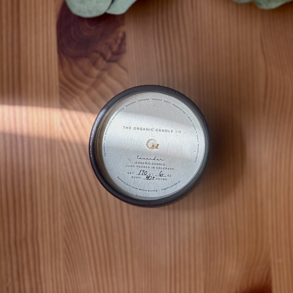 Top-down view of a round black ceramic organic candle with a white label reading &