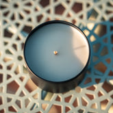 Black organic candle on a blue decorative surface