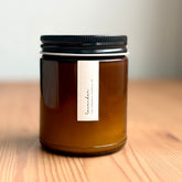 Amber jar organic candle with black lid on a wooden surface