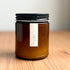 Amber jar organic candle with black lid on a wooden surface
