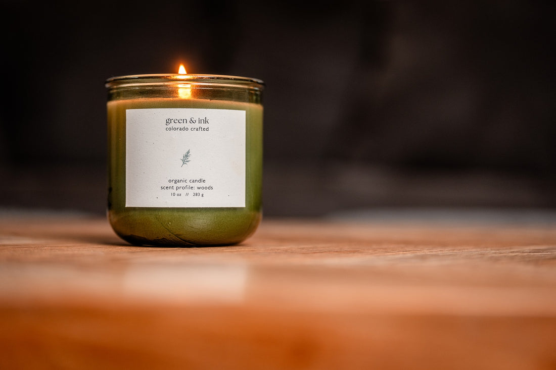 Organic candle in recycled green glass with a label on a wooden surface