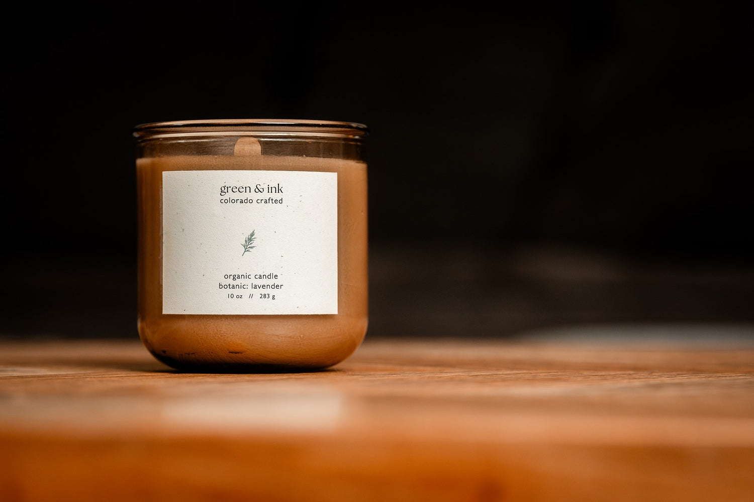 Organic candle in recycled blush-colored glass with a label on a wooden surface