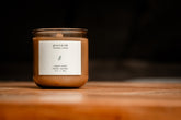 Organic candle in recycled blush-colored glass with a label on a wooden surface