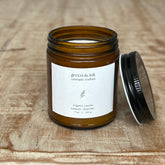 Brown glass candle jar with a white label on a wooden surface