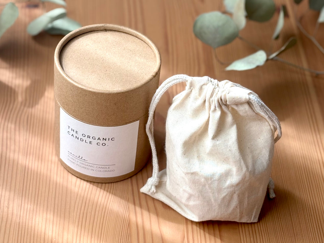 Cylindrical container with a label and a drawstring bag on a wooden surface with eucalyptus leaves.
