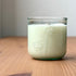 Organic candle in a recycled glass floral jar on a wooden surface