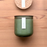 Organic candle in green recycled glass jar on a wooden background. A label reads "lavender; The Organic Candle Co."